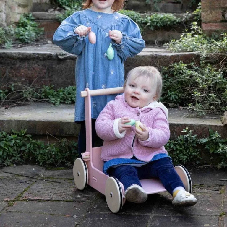 Two children playing with a pink scooter on stone steps.