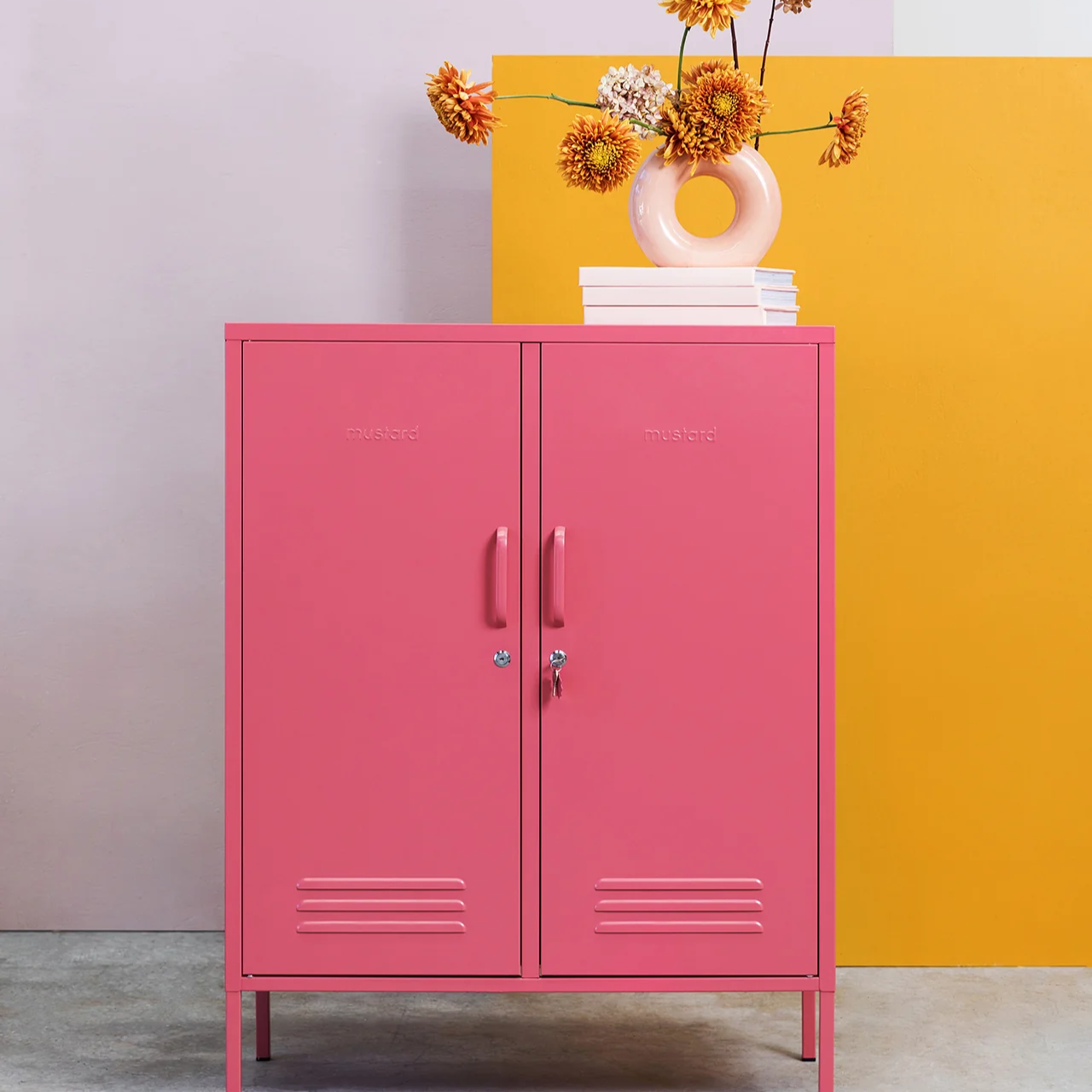 Pink cabinet with a vase of flowers against a colorful wall