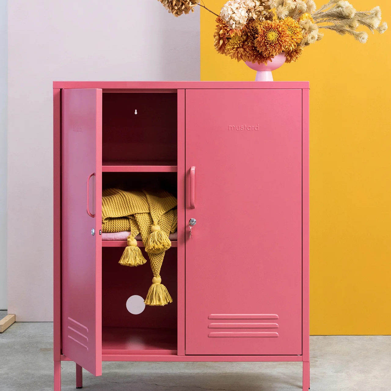 Pink cabinet with yellow interior against a pink and yellow wall