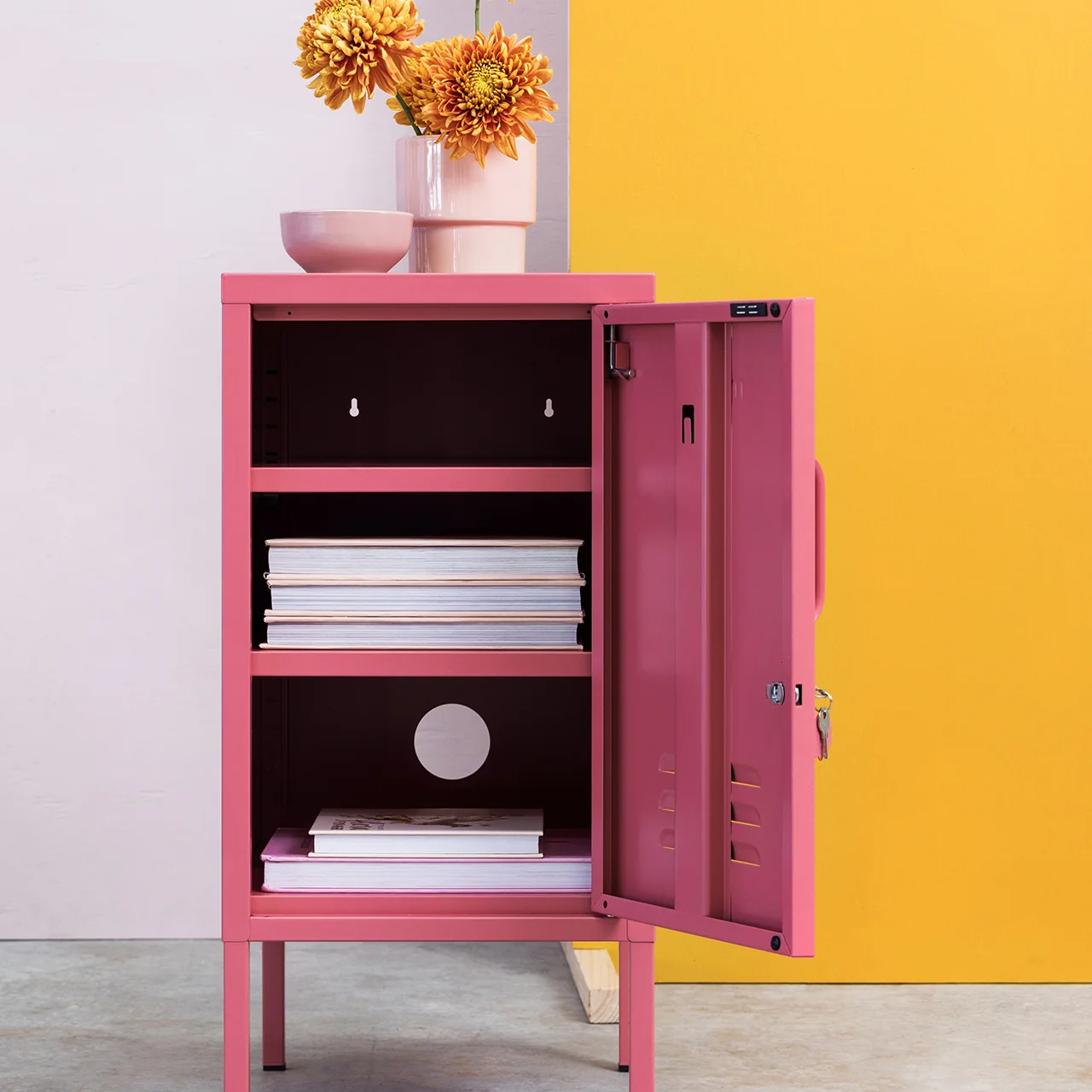 Pink cabinet with open door against a yellow and white wall