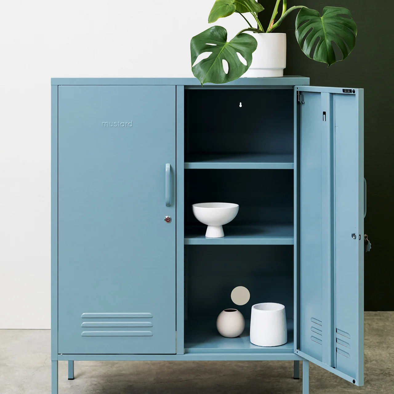 Blue metal cabinet with open doors displaying interior shelves and decorative items, against a neutral background.