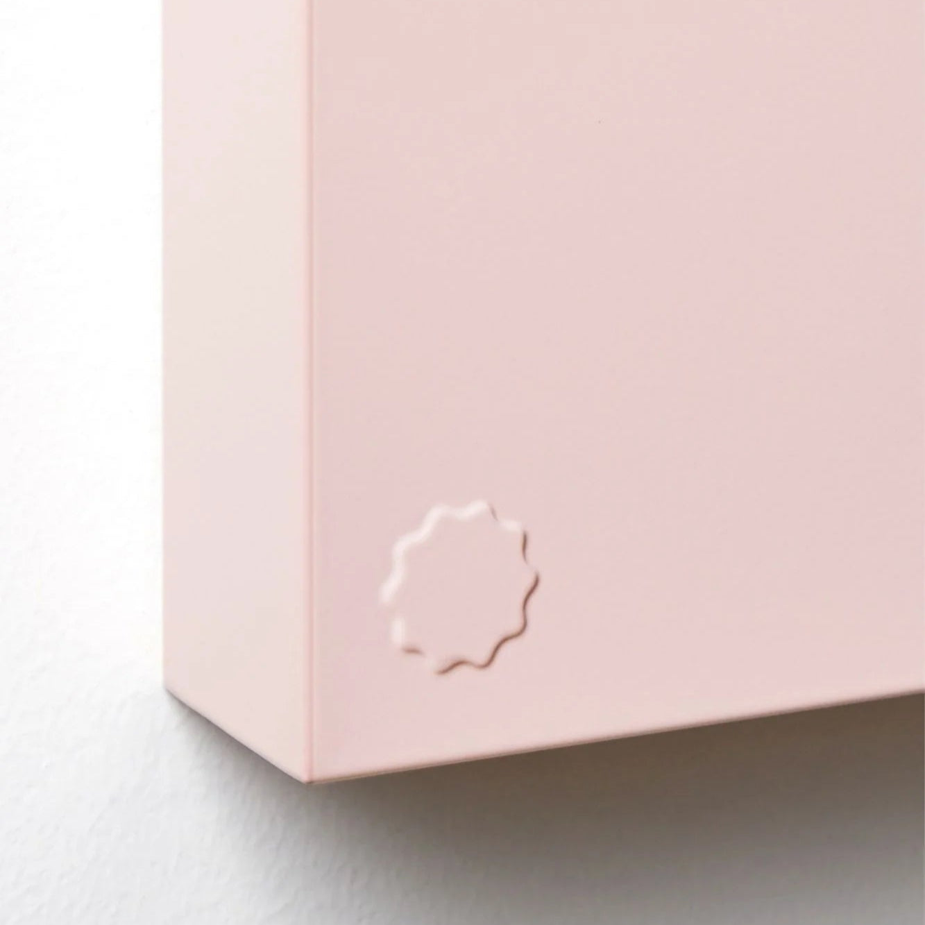Close-up of a pink box with a brand logo on a light gray background