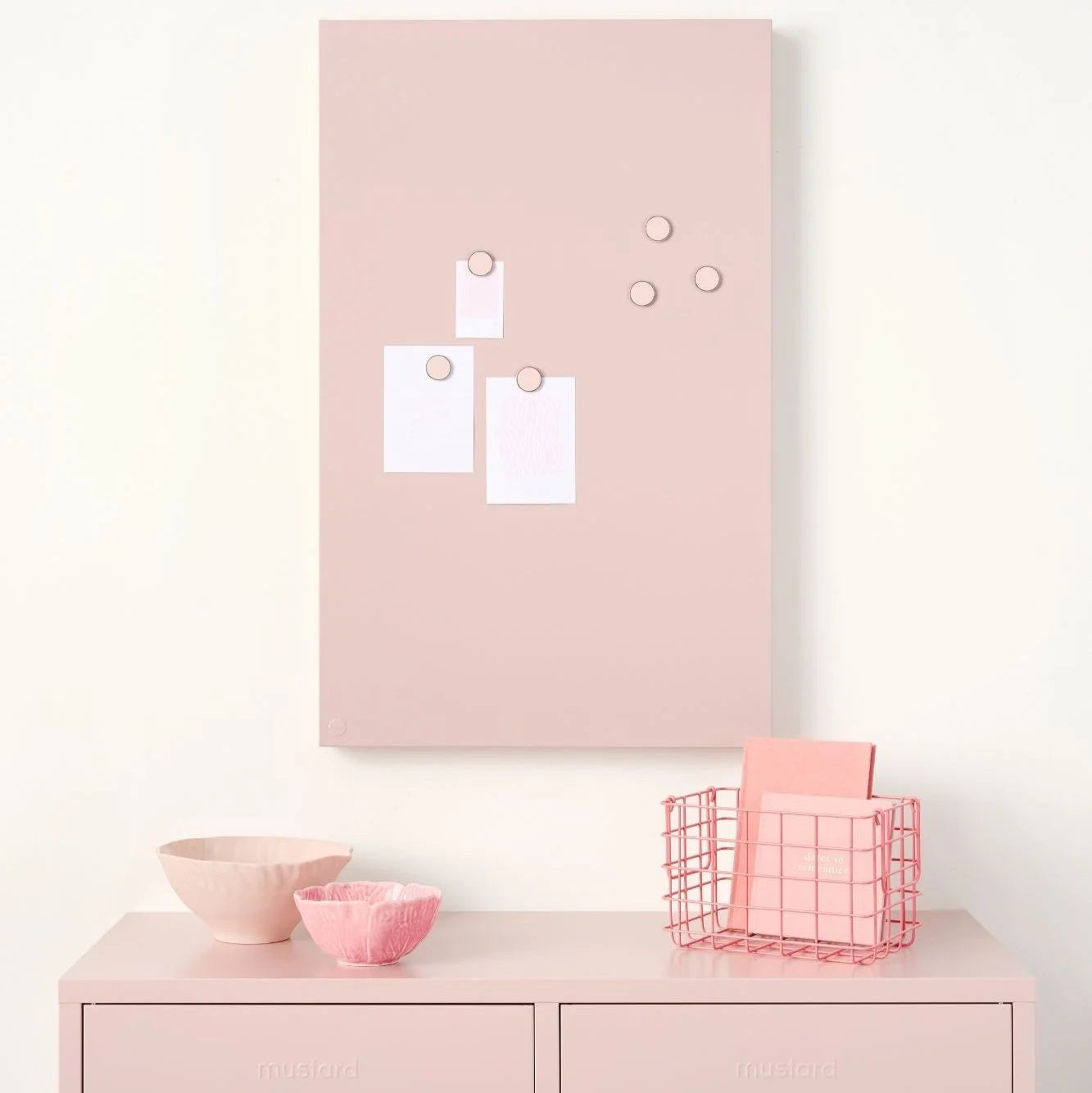 Pink cabinet with a pink memo board above it on a white wall.