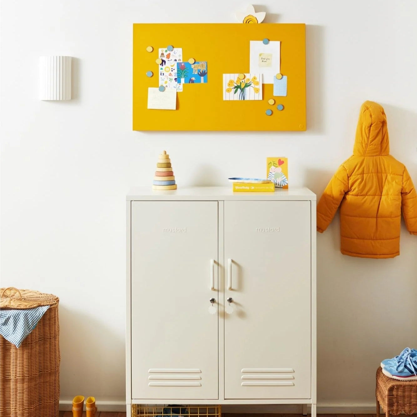 Yellow bulletin board with notes on a white wall above a white locker in a room.