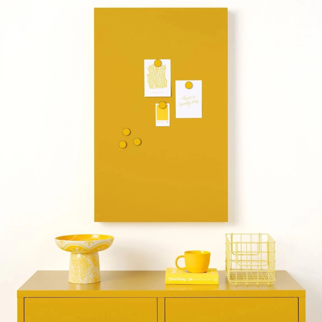 Yellow cabinet with a matching yellow magnetic notice board on a white wall.