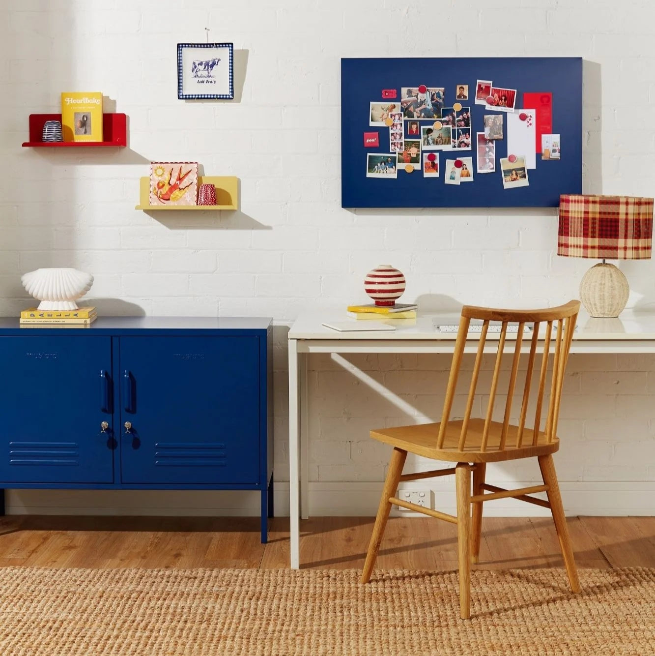 White cabinet with decorative items in a room with a blue wall art piece.