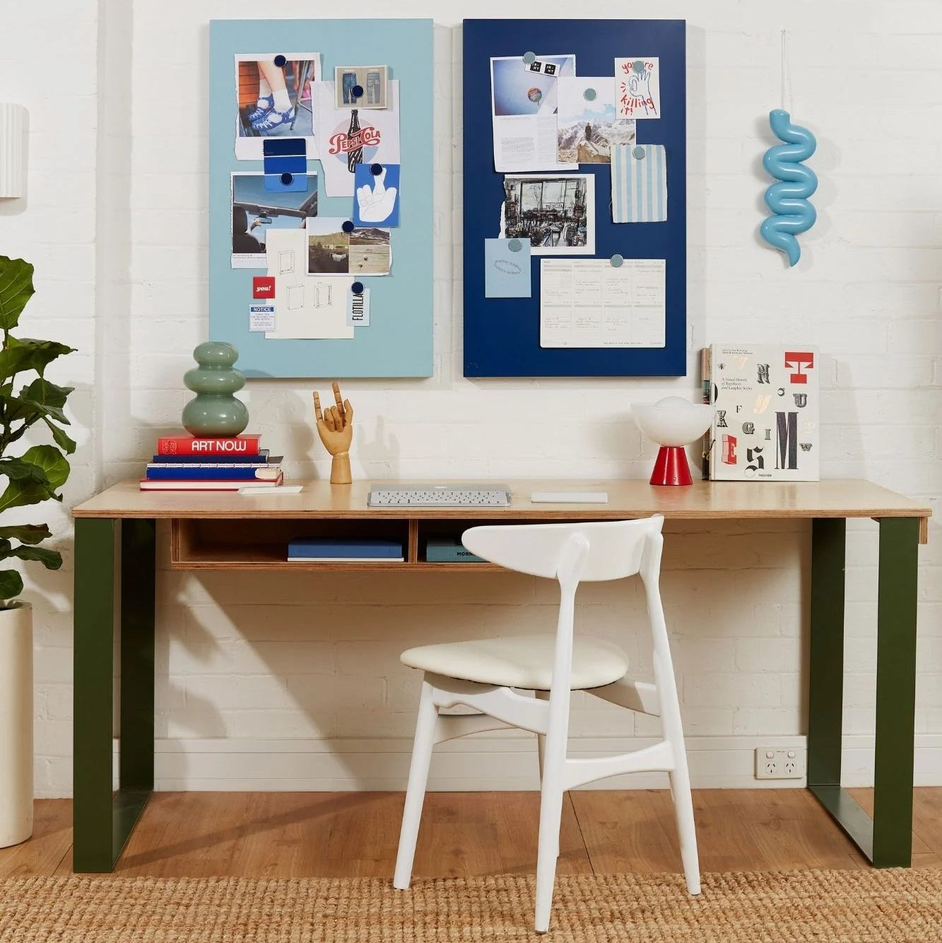 Home office setup with a desk, chair, and decorative elements on a white wall.