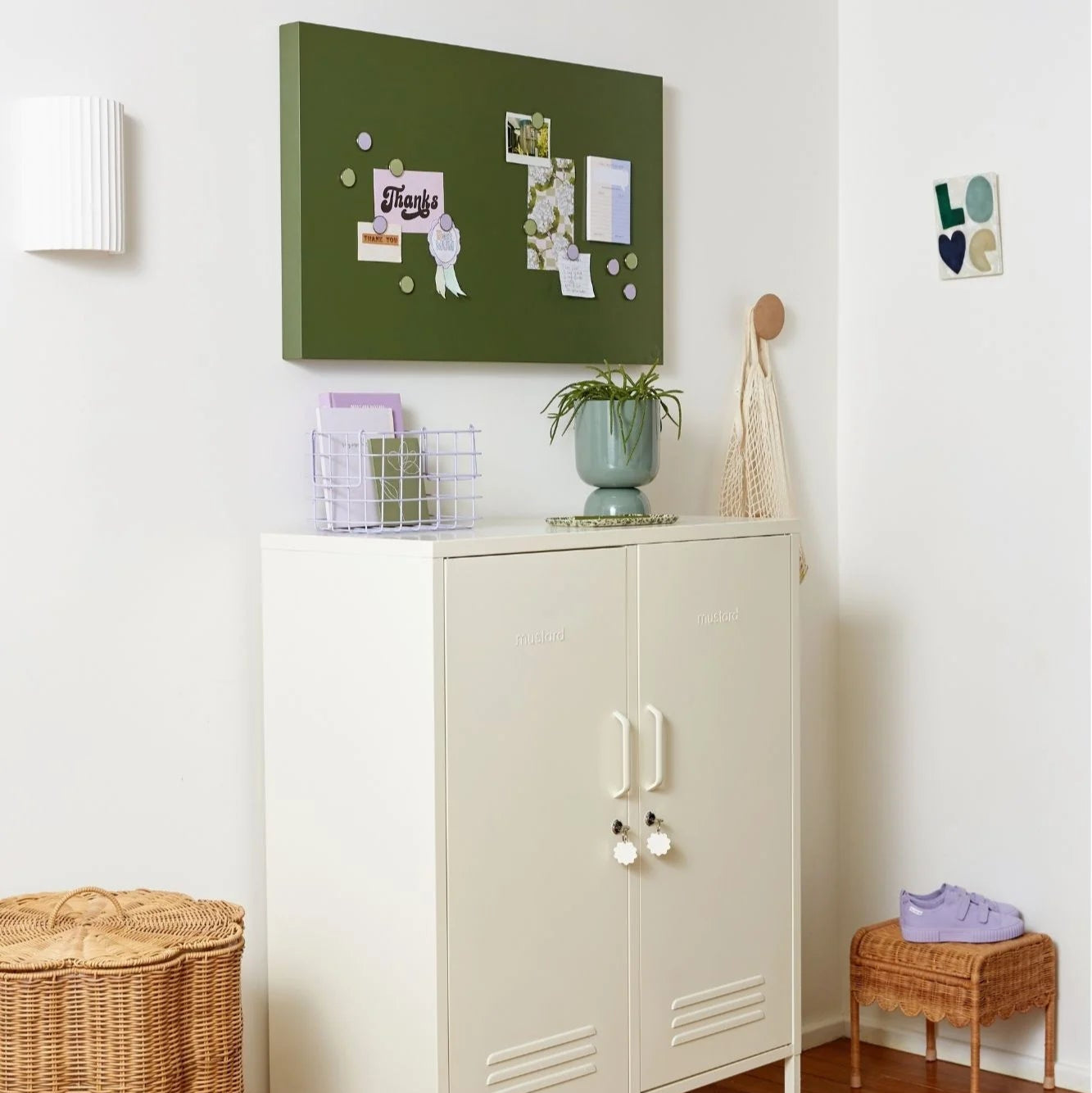 White cabinet with a green bulletin board above it in a room setting.