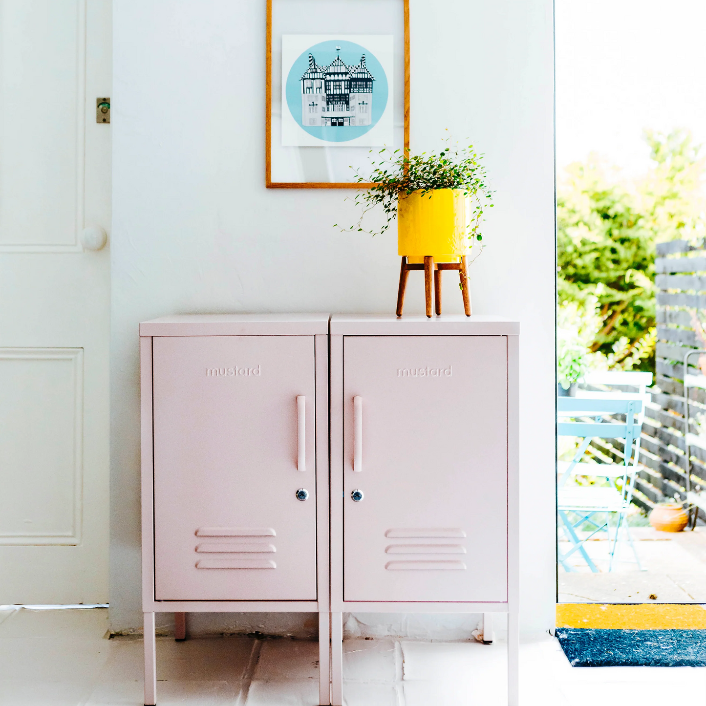 Pink cabinets opening either side with a clock and framed picture on a white wall.