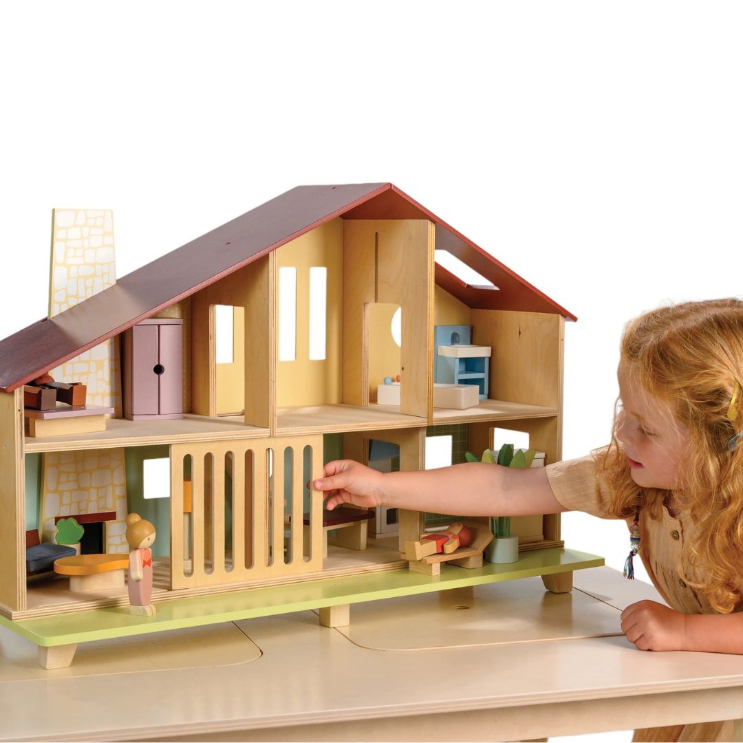 Wooden dollhouse with furniture and toys on a white background