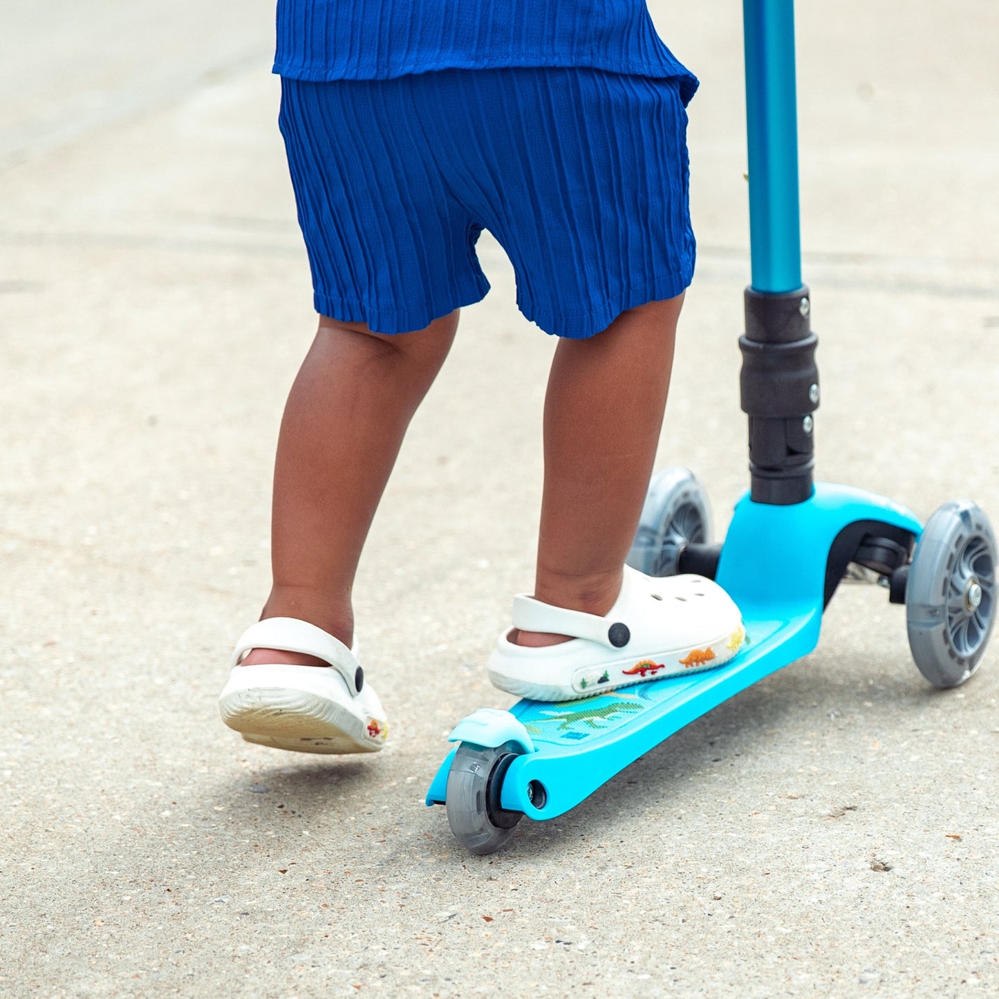Child riding a blue scooter on a concrete surface