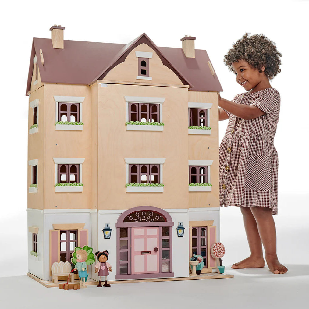 Child playing with a dollhouse and dolls on a white background