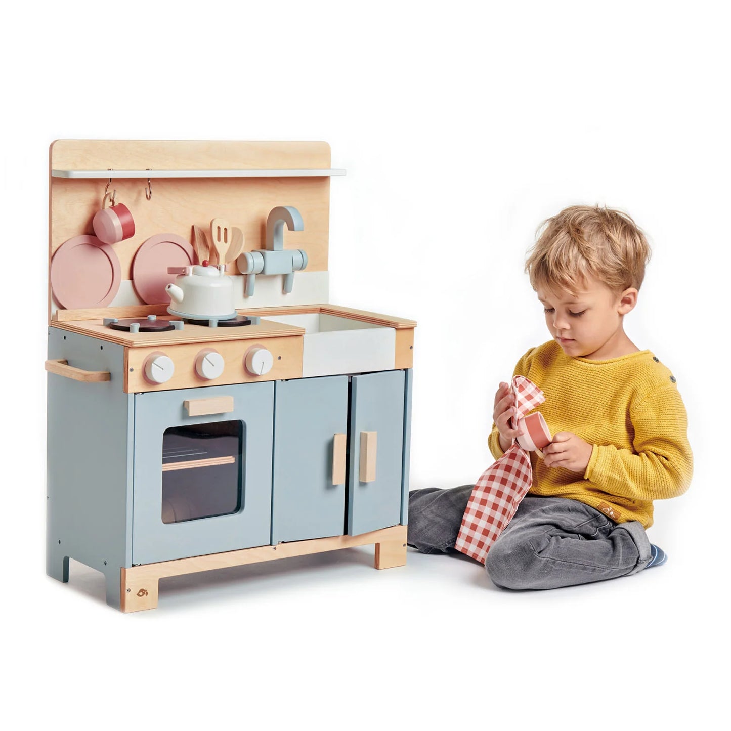 Child playing with a toy kitchen set on a white background