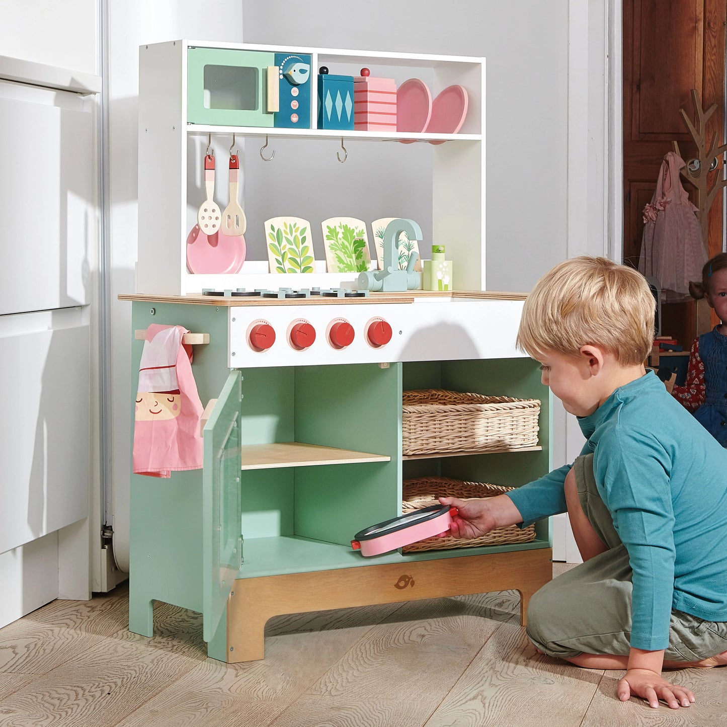 Child playing with a toy kitchen set in a room.