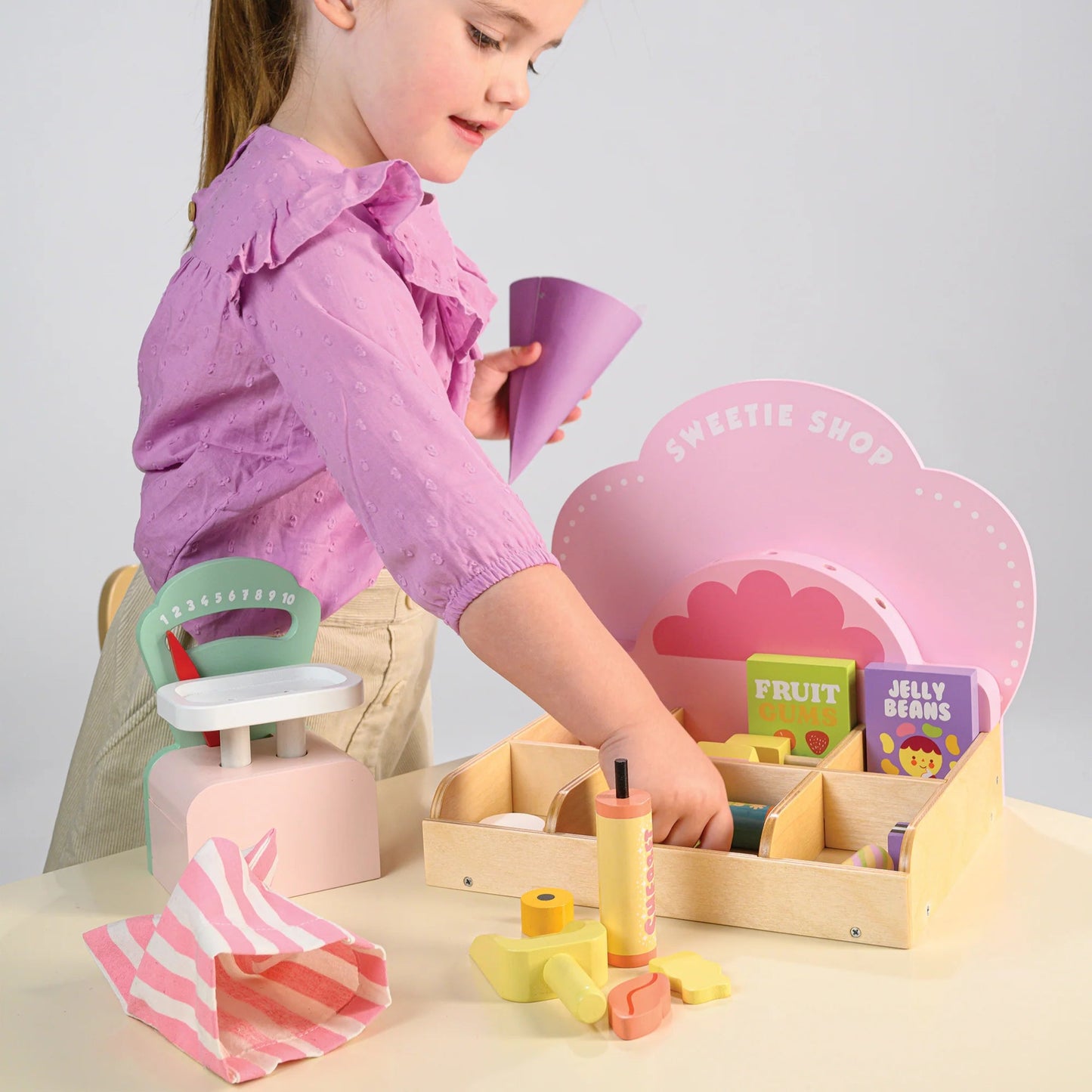 Child playing with a toy set on a table against a plain background