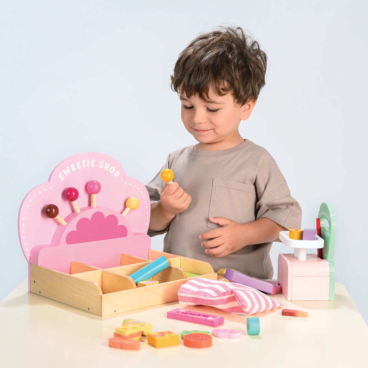 Child playing with a wooden toy set on a light blue background