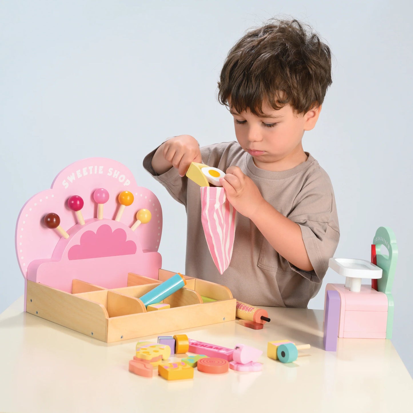 Child playing with a toy ice cream shop set on a light gray background