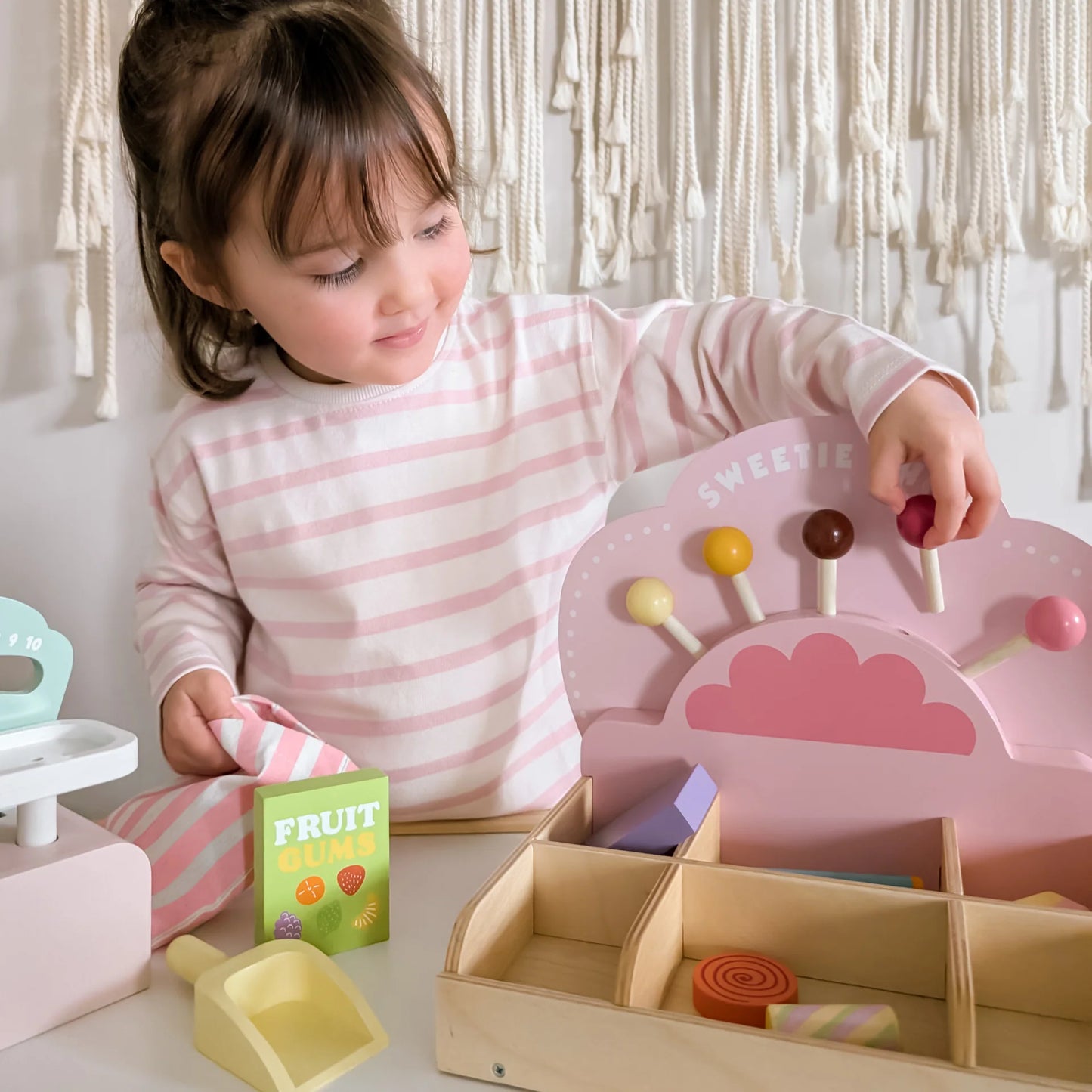 Child playing with a toy ice cream set and educational cards on a light-colored surface.