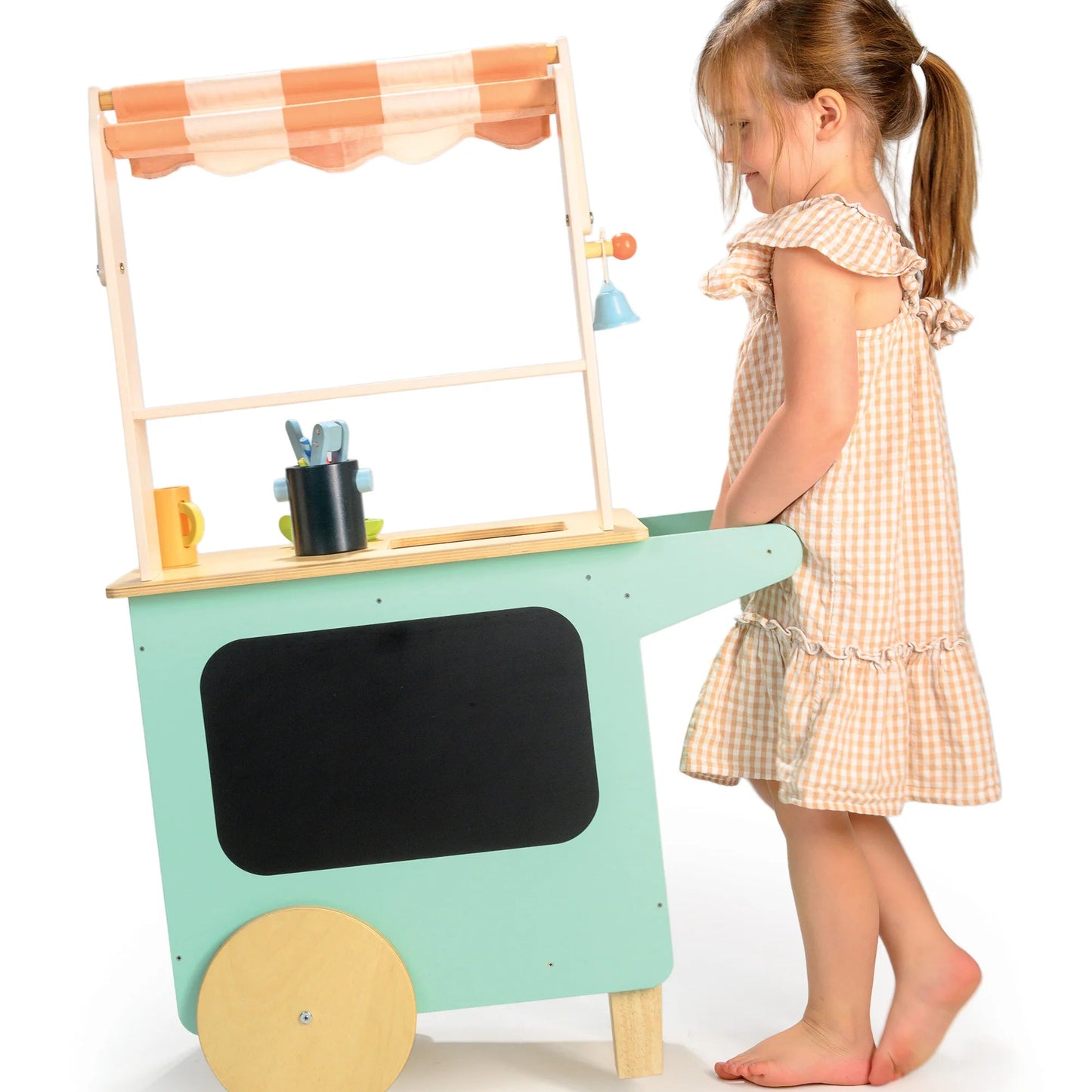 Child playing with a toy kitchen cart on a white background