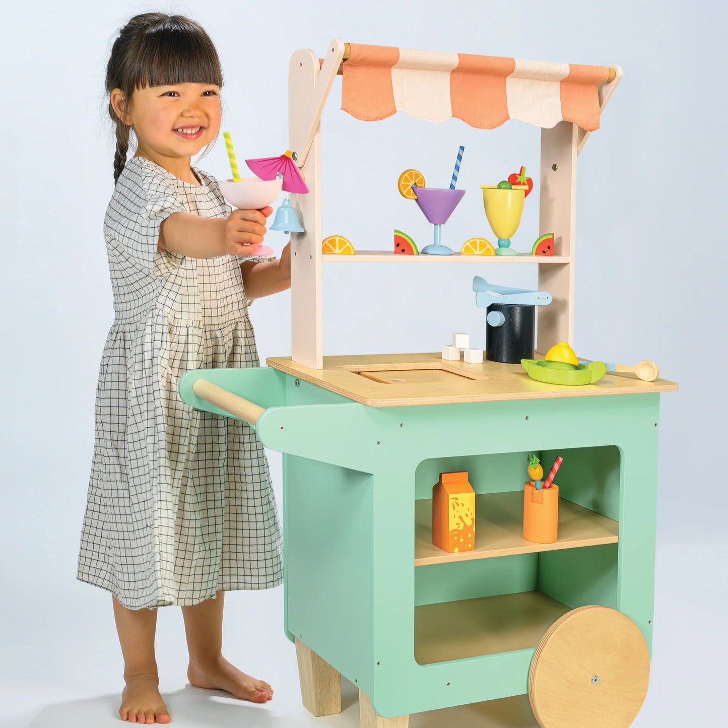 Child playing with a toy kitchen set on a light blue background