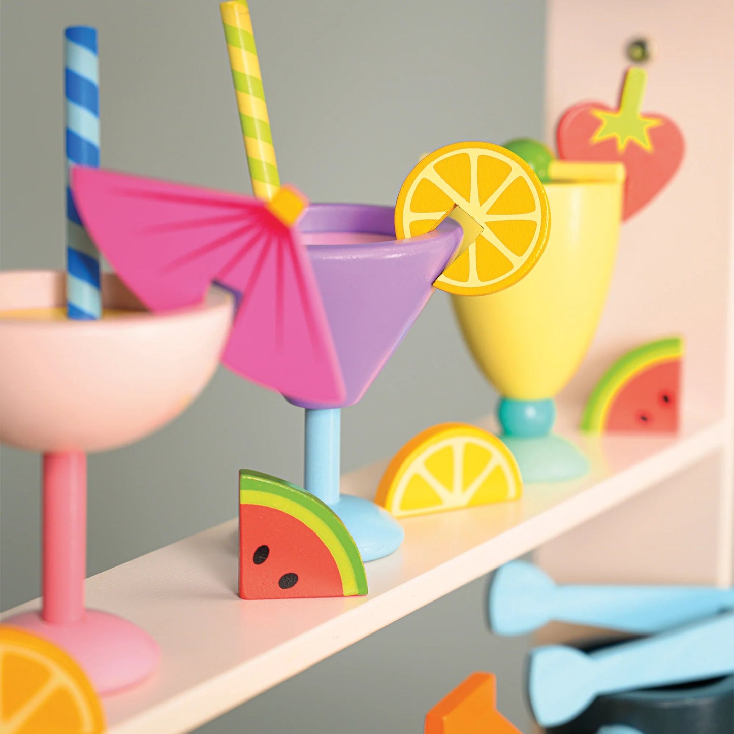 Colorful toy drink set with cups, straws, and lemons on a shelf.