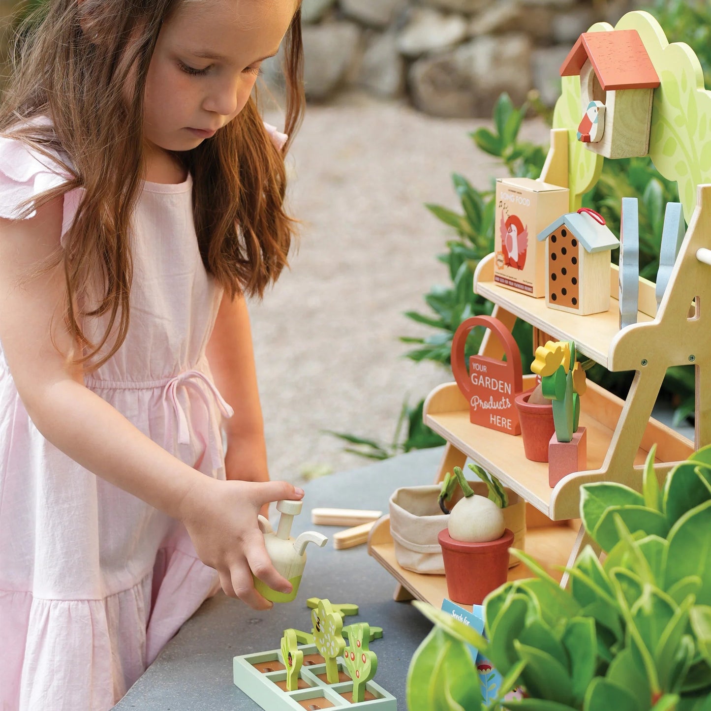 Young girl playing with a toy garden set outdoors