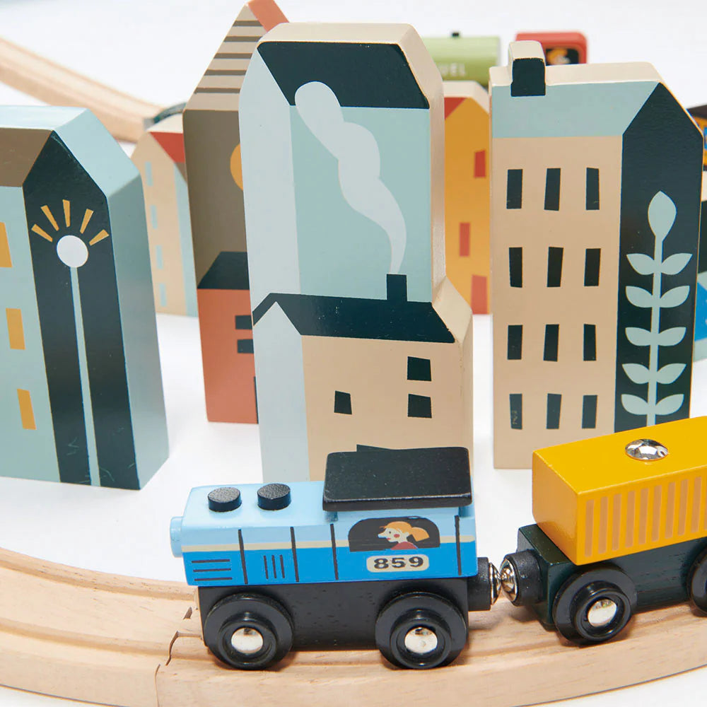 Wooden toy train set on tracks with colorful buildings in the background