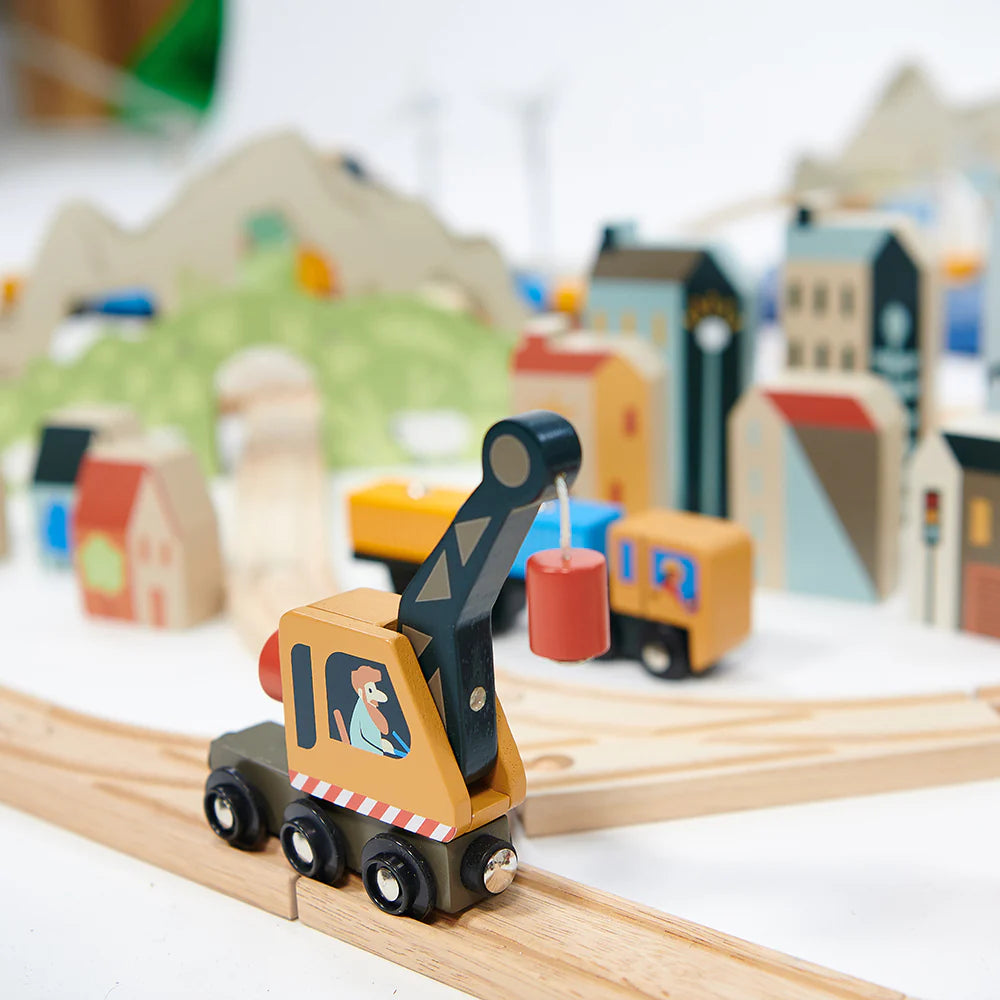Wooden toy crane on a track with a blurred model cityscape in the background