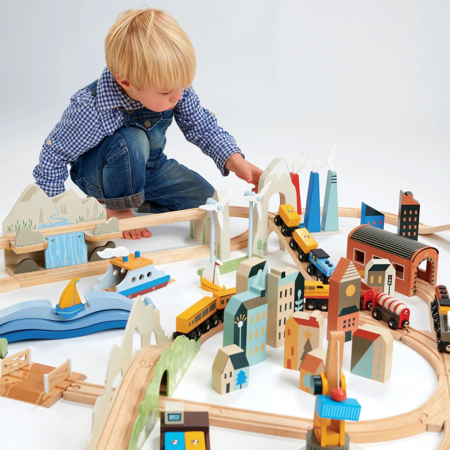 Child playing with a wooden train set on a white background