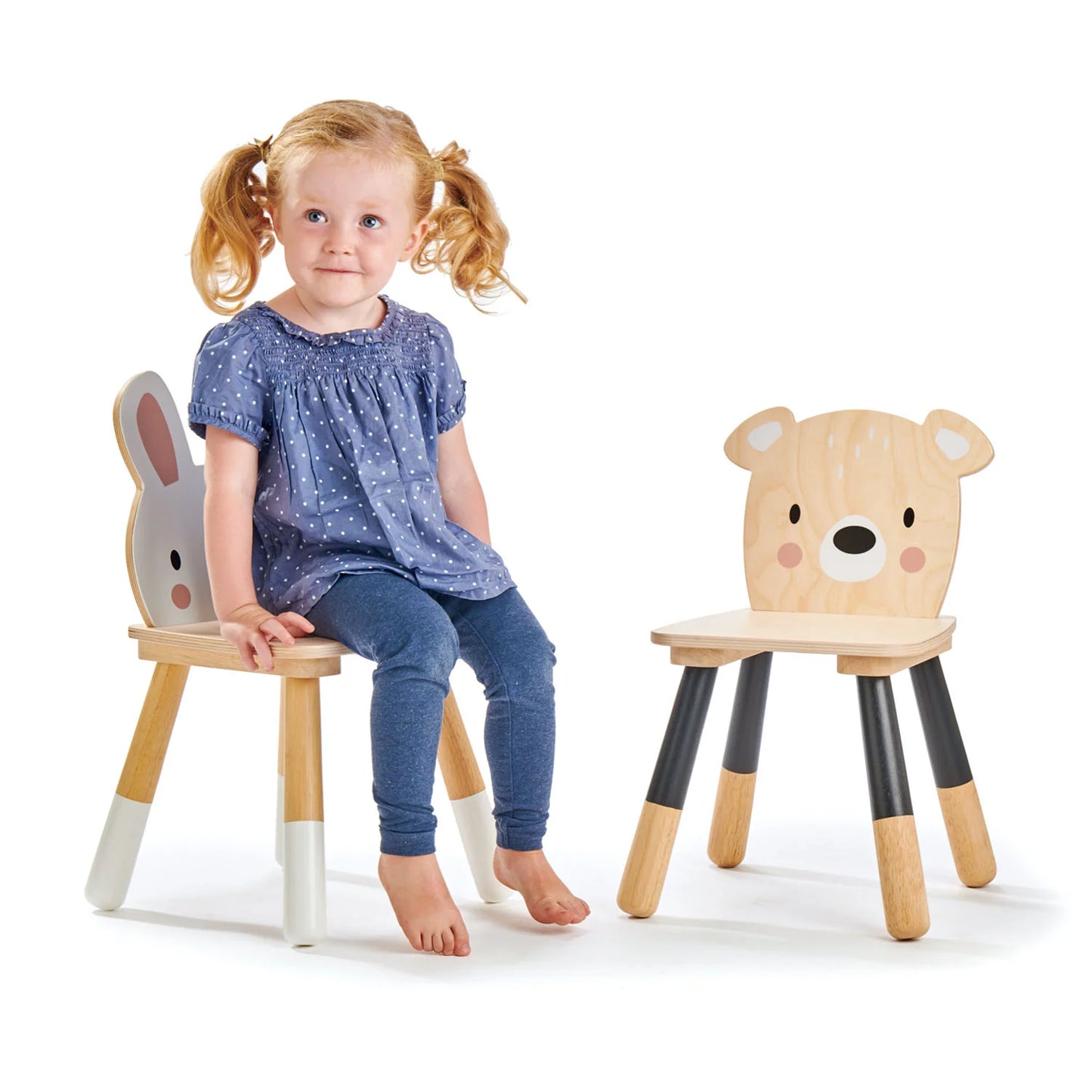 Child sitting on a wooden chair with animal face design, next to another similar chair.