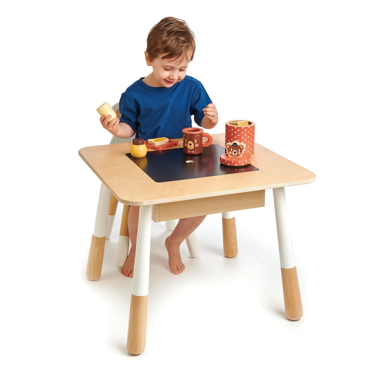 Child playing with toys at a small wooden table on a white background