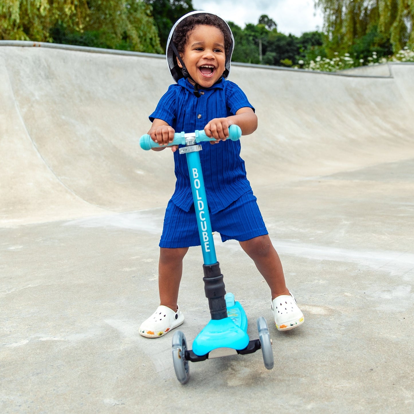 Child riding a blue scooter at a skate park