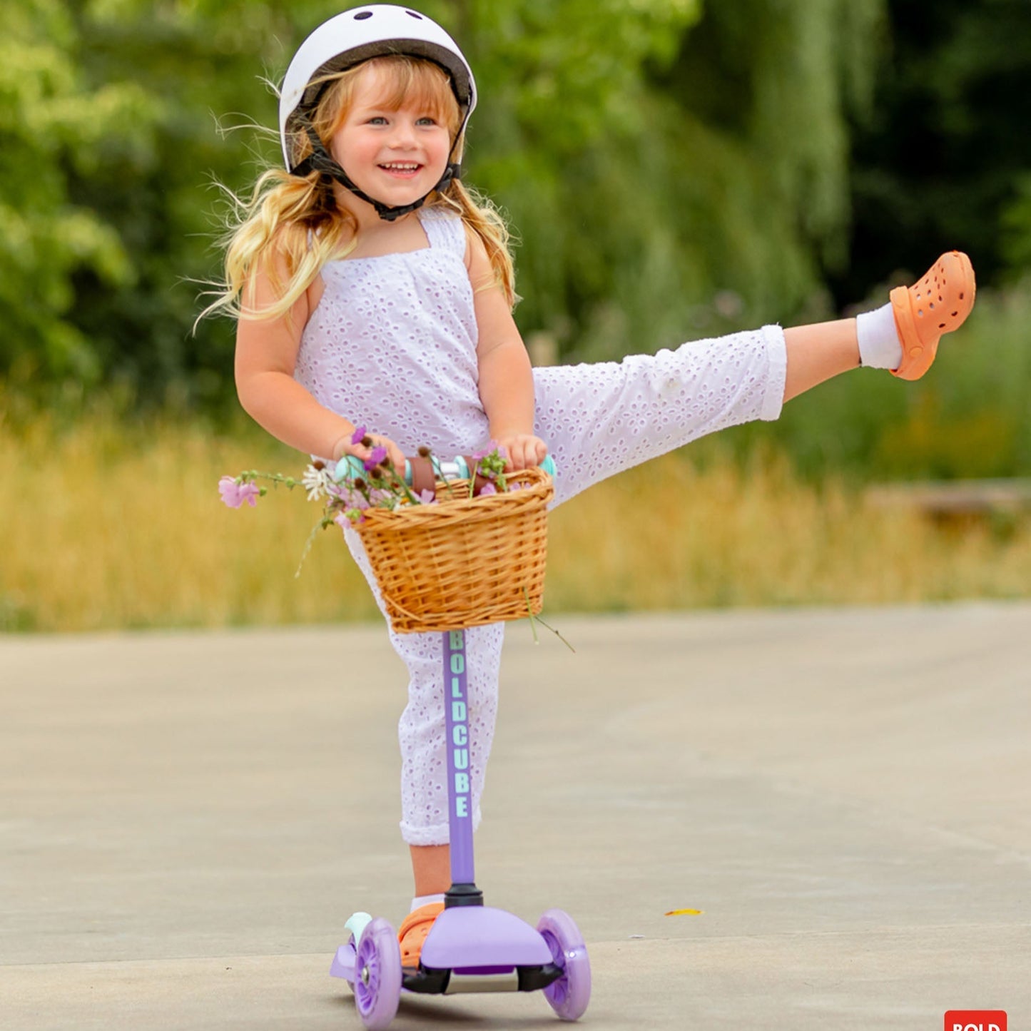 Child riding a scooter with a basket full of flowers outdoors