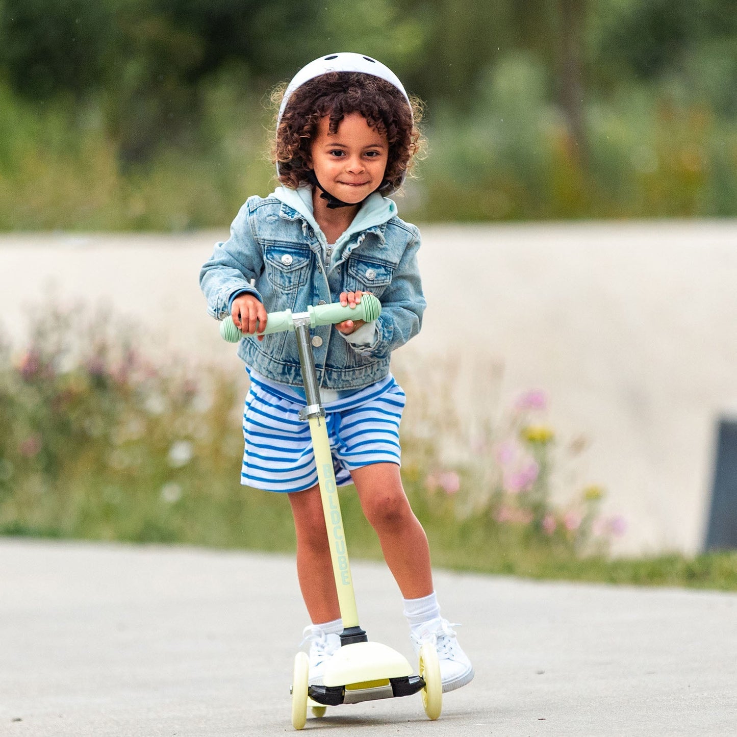 Child riding a scooter outdoors with a blurred natural background