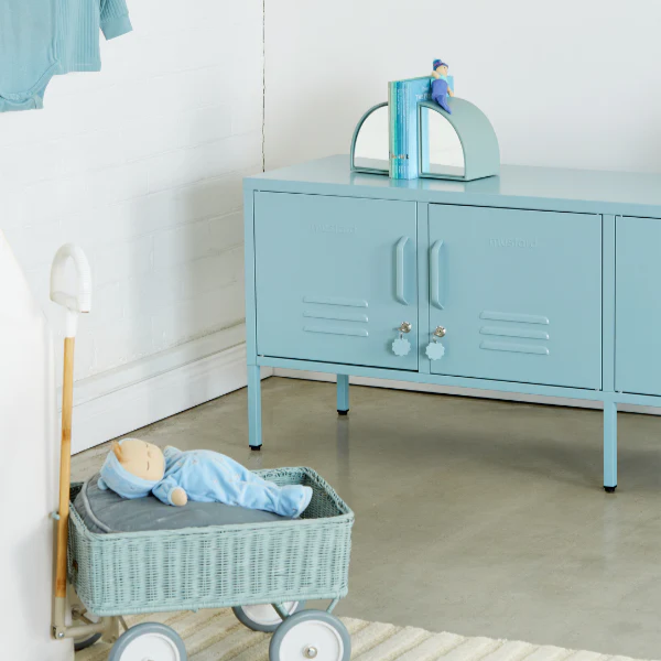 Children's room with blue cabinet, toy cart, and baby doll.