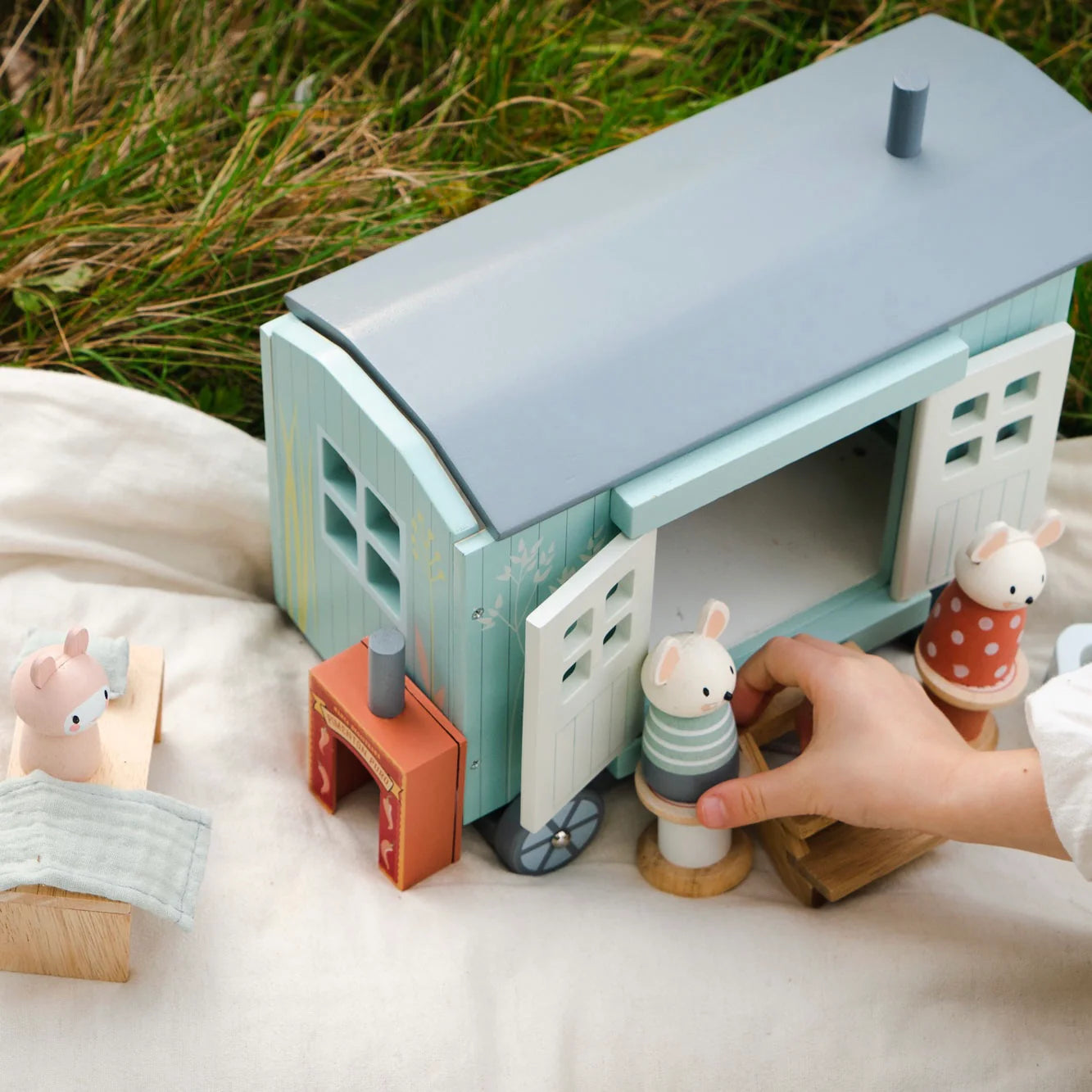 Children's toy train set with wooden figures on a grassy background