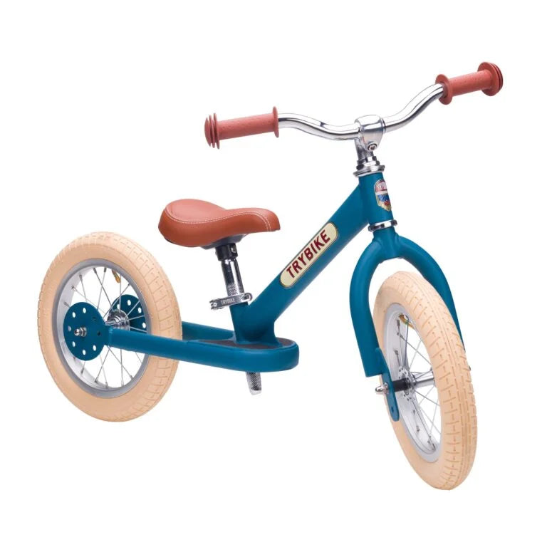 Blue balance bike with brown seat and handlebar grips on a white background