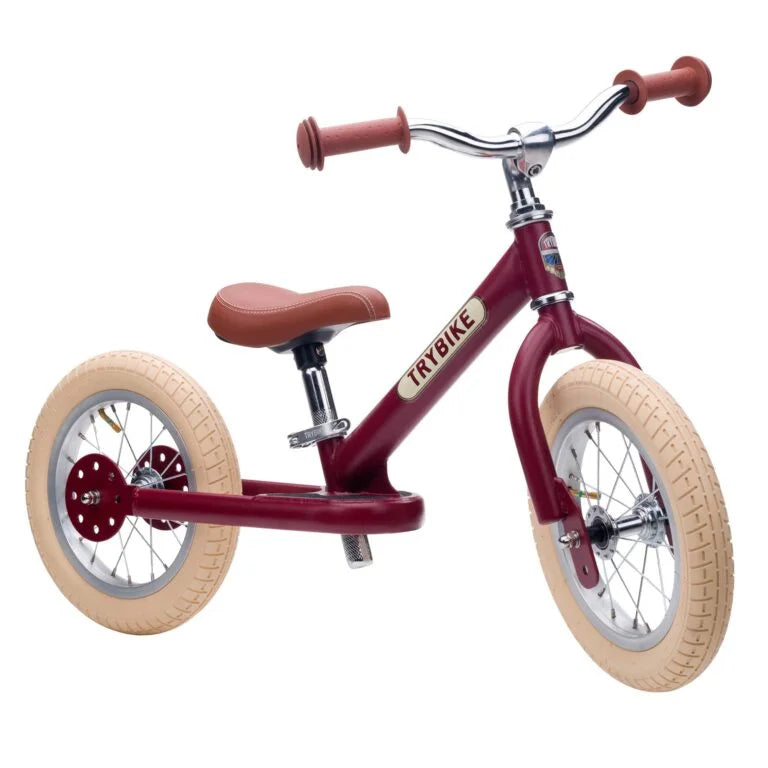 Red balance bike with beige tires on a white background