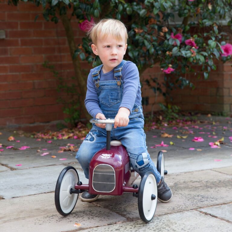 Burgundy ride on toy car with child riding on it