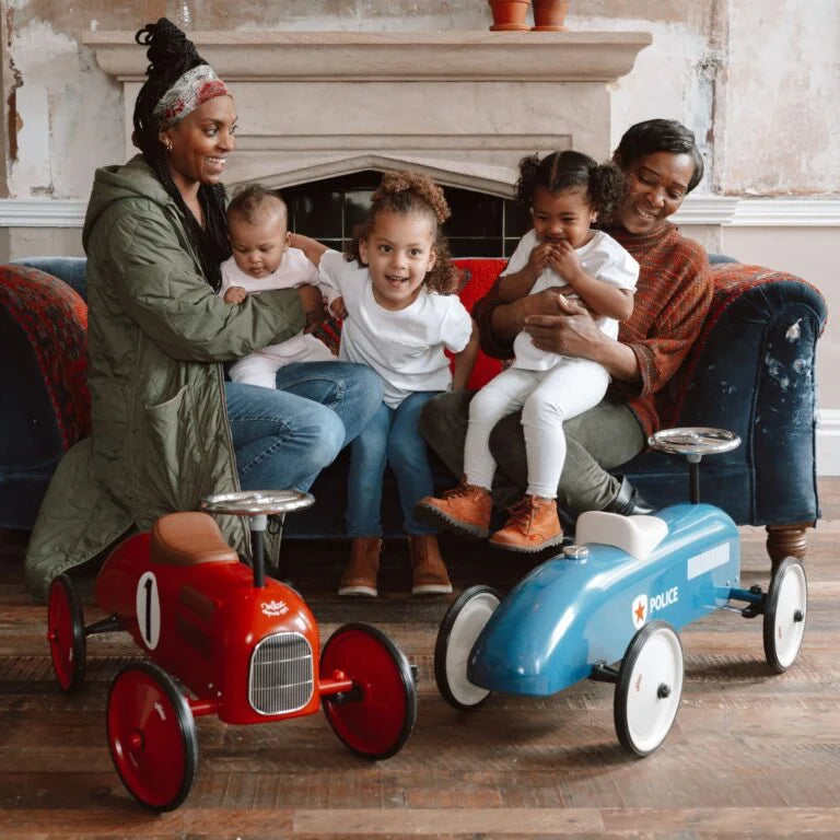 Red ride on toy car in a room with a family