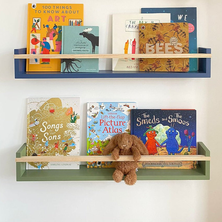 Children's books on wooden shelves against a white wall