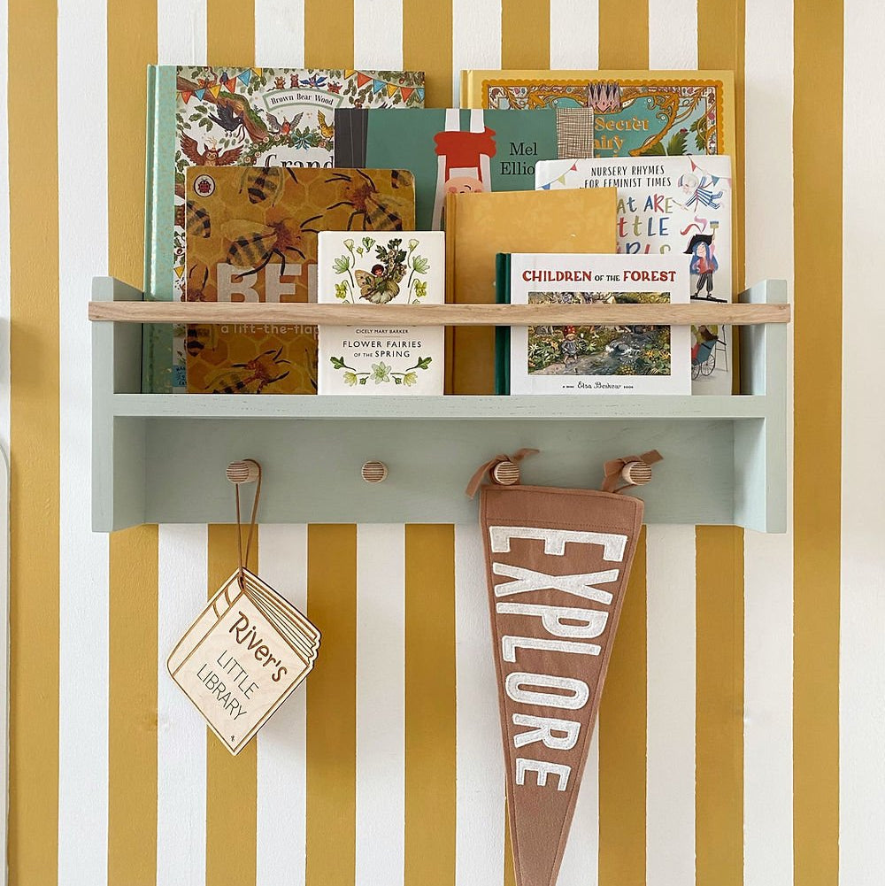 Children's books and a pennant on a shelf against a striped wall.