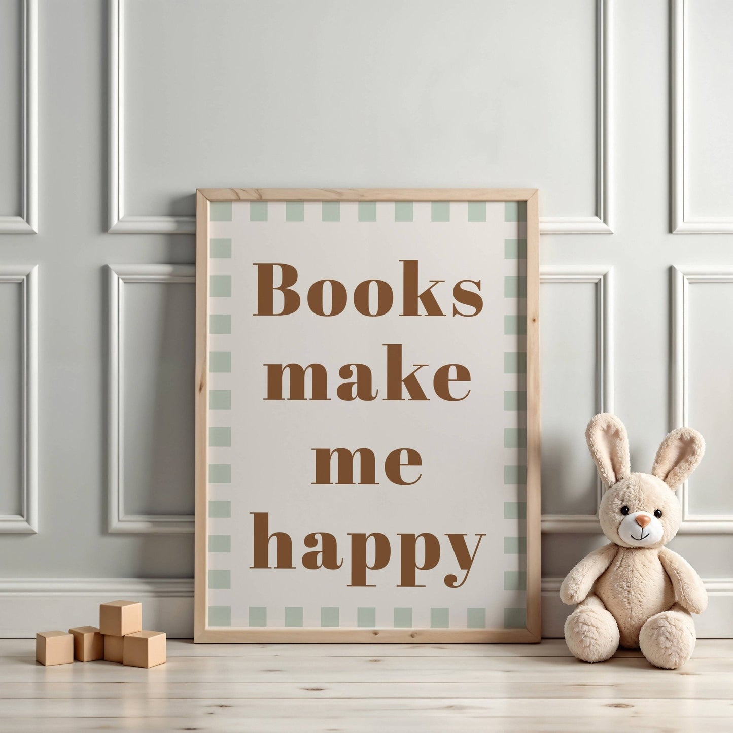 Framed poster with 'Books make me happy' text on a wall with a teddy bear and wooden blocks.