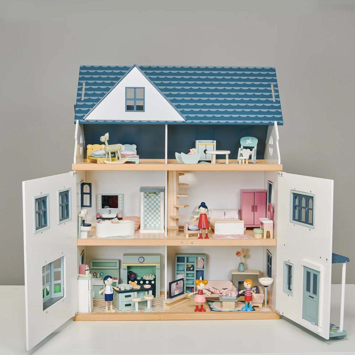 Wooden dollhouse with open doors showing different rooms and furniture on a gray background