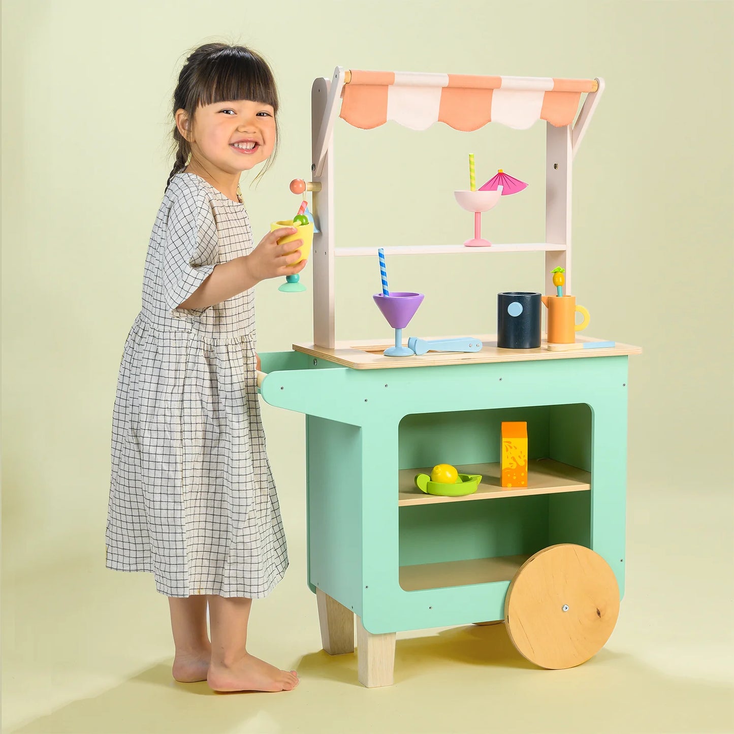 Child playing with a toy kitchen set on a light green background