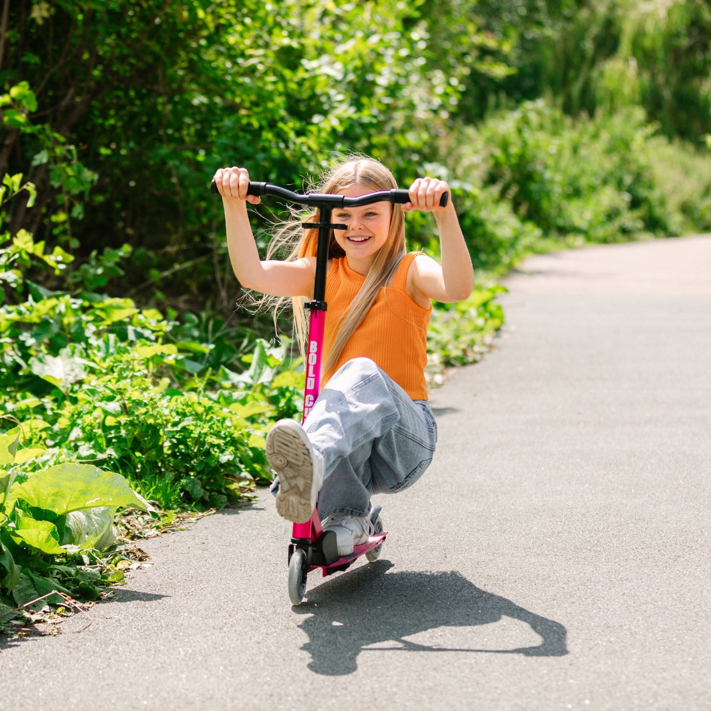 Child riding a scooter on a sunny day with greenery around