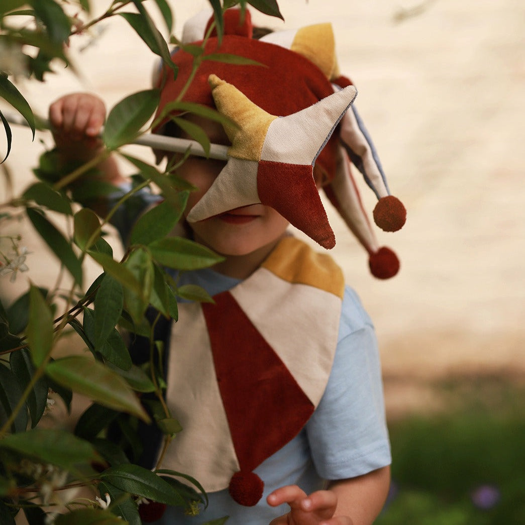 Child wearing a colorful unicorn horn hat in a natural setting