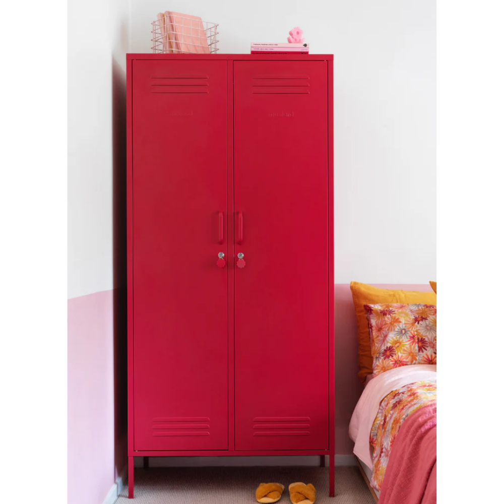Red metal cabinet in a room with a bed and colorful bedding.