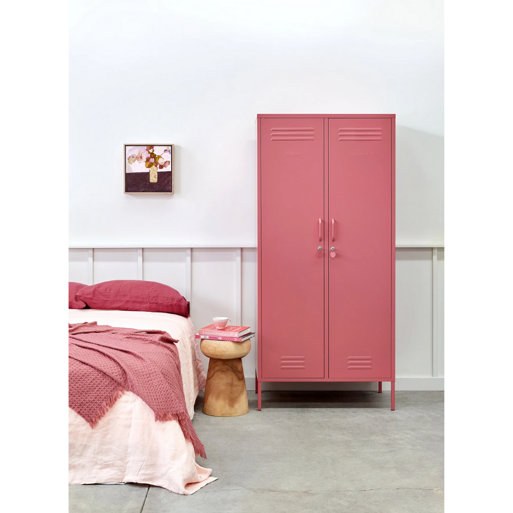 Pink metal locker in a bedroom with a bed and wooden stool.