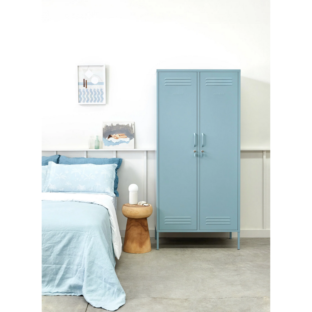 Blue cabinet next to a bed with light blue bedding in a bedroom setting.